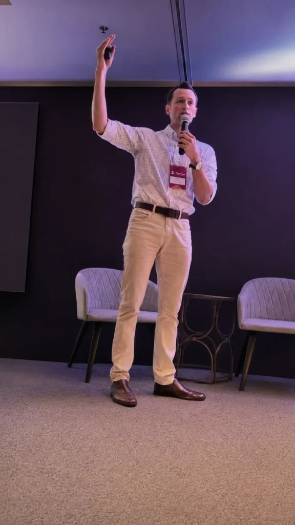 André conduzindo um treinamento no palco, com microfone na mão